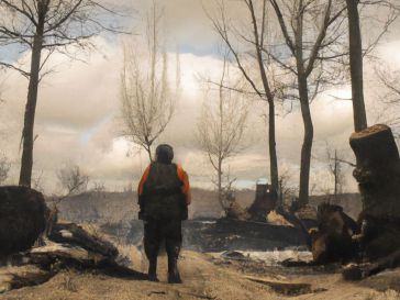 Un soldado ruso se encuentra en medio de la devastación causada por el ataque, con los restos de un tanque a su lado. El cielo está cubierto de nubes grises y el frío viento sopla entre los árboles desnudos.